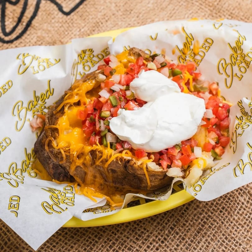 A Baked and Loaded baked potato with melted cheese, pico de gallo, and sour cream.